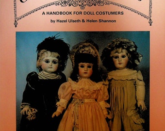 Pode incluir: Capa de livro intitulada "ANTIQUE CHILDREN'S FASHIONS 1880-1900" com três bonecas antigas. O livro é um manual para costureiros de bonecas de Hazel Ulseth & Helen Shannon. As bonecas usam vestidos e chapéus antigos.