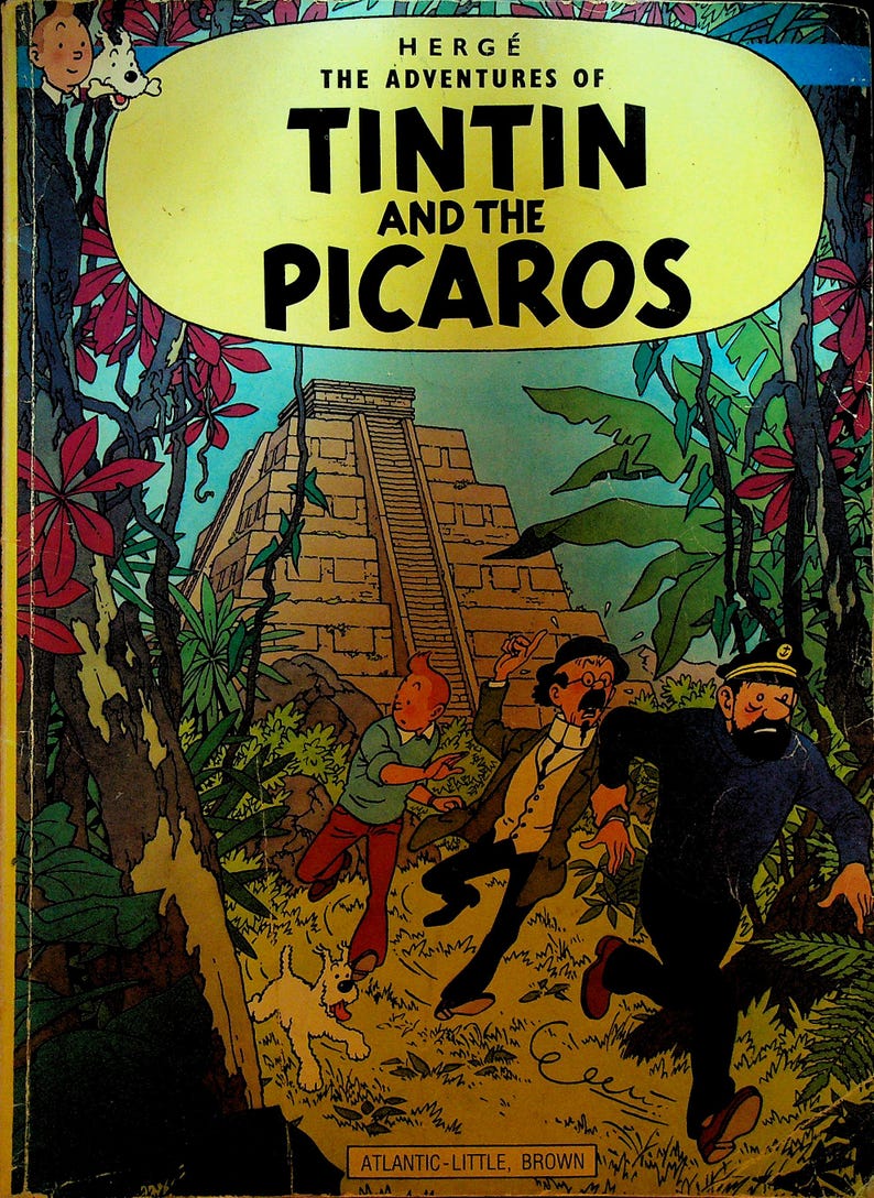 May include: Cover of "The Adventures of Tintin and the Picaros" comic book. The cover features a yellow banner with the title, and illustrations of Tintin, Captain Haddock, and others running from a pyramid in a jungle setting.