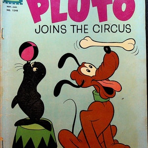 May include: A vintage comic book cover featuring Pluto the dog, a cartoon character from Walt Disney's animated films. Pluto is wearing a green collar and is balancing a bone on his nose. He is sitting on a red and black circus ring. A black and white seal is balancing a pink ball on its nose. The comic book cover is titled "Walt Disney's Pluto Joins the Circus" and is from November-January 1961.