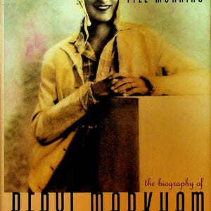 May include: Book cover featuring a sepia-toned image of a person in a vintage aviator helmet and goggles. The title "STRAIGHT ON TILL MORNING" is at the top, with "BERYL MARKHAM" prominently displayed below. The text "the biography of" is also visible.