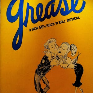 Puede incluir: Un póster amarillo con el título "Grease" en letras azules. El póster anuncia un nuevo musical de rock and roll de los años 50. El póster presenta una imagen de dibujos animados de una pareja bailando.