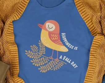May include: A blue t-shirt with a cartoon bird on a branch. The bird is yellow with red accents and closed eyes. The text "Happiness is a Fall Day" is written on the shirt.