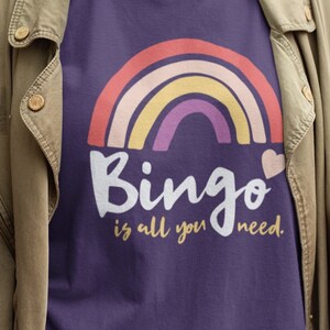 May include: Purple t-shirt with a rainbow and the text "Bingo is all you need."