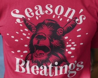 May include: A red t-shirt with a white graphic of a goat with the text "Season's Bleatings".