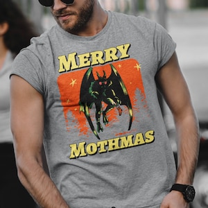 May include: A grey heather t-shirt with a graphic print of a green monster with red eyes and the text "Merry Mothmas".