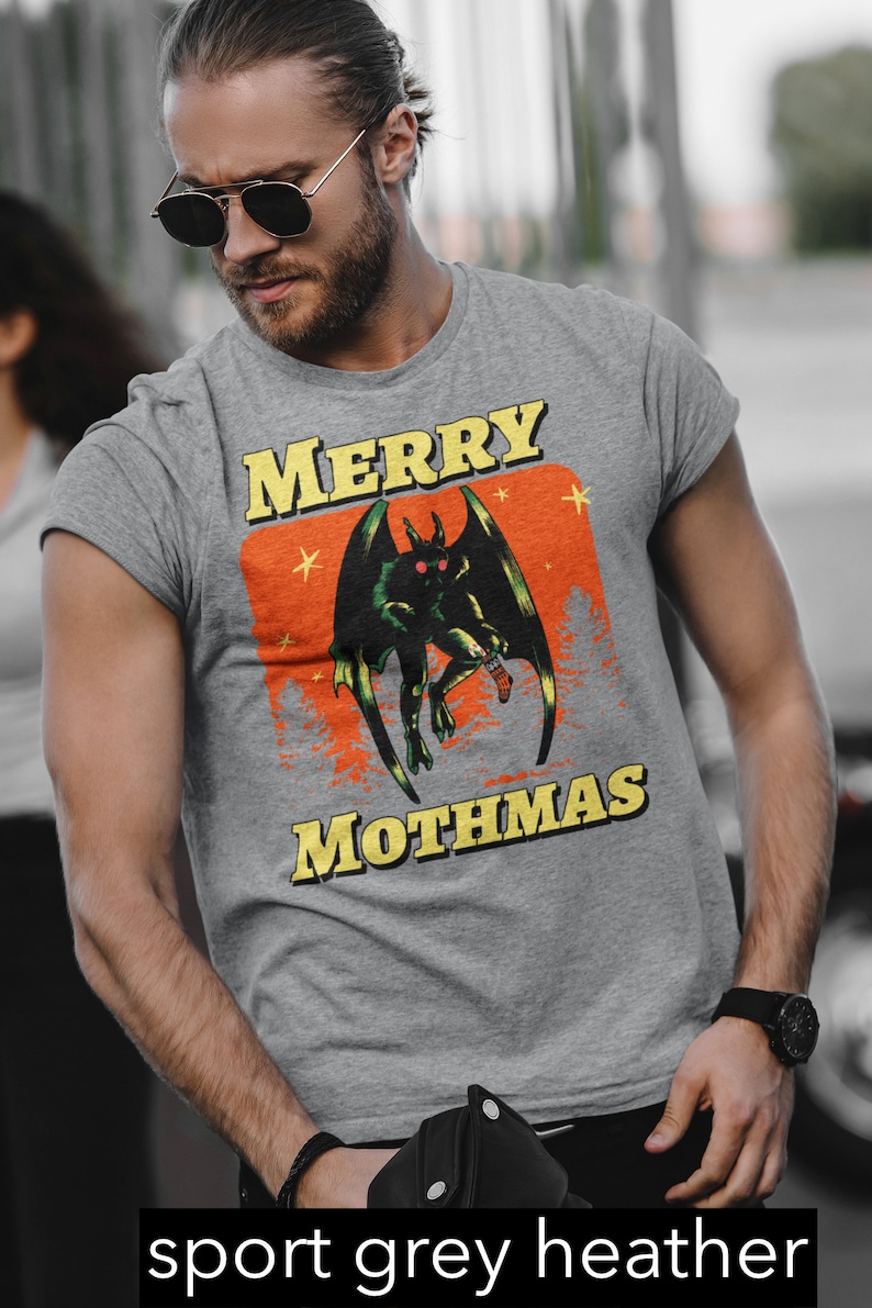 May include: A grey heather t-shirt with a graphic print of a green monster with red eyes and the text "Merry Mothmas".