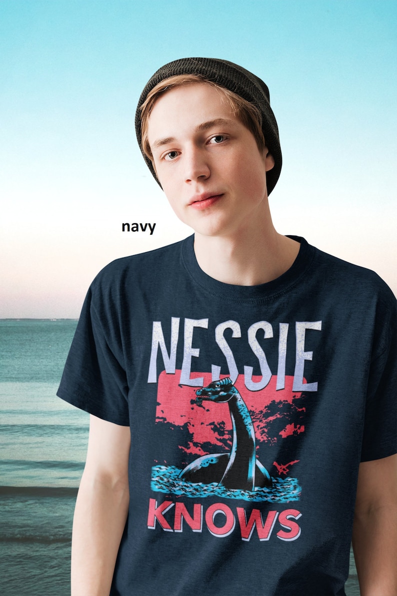 May include: A navy blue t-shirt with a graphic of Nessie, the Loch Ness Monster, and the text "Nessie Knows".