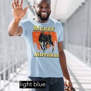 May include: A light blue t-shirt with a graphic of a green monster with red eyes and the text "Merry Mothmas".