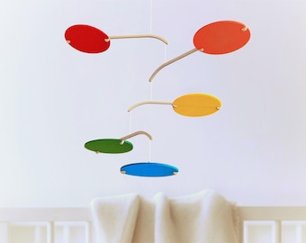 Puede incluir: Un móvil colorido con cinco piezas de madera ovaladas en rojo, naranja, amarillo, verde y azul colgando de un marco de madera.