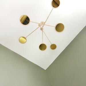 Può includere: Un soffitto bianco con un mobile in legno appeso. Il mobile ha sei specchi rotondi dorati.