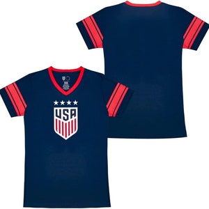 May include: Navy blue V-neck t-shirt with red accents. The shirt features red stripes on the sleeves and collar. The front displays the USA logo with stars above it. The shirt is a sporty design.