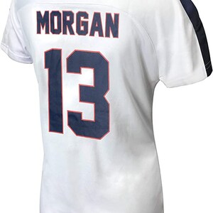 K&ouml;nnte beinhalten: Wei&szlig;es Fu&szlig;balltrikot mit blauem und rotem Besatz. Auf der R&uuml;ckseite des Trikots sind der Name "MORGAN" und die Nummer "13" in Blau mit rotem Umriss gedruckt.