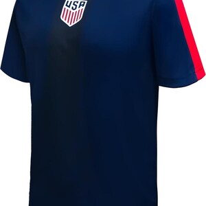May include: Navy blue athletic t-shirt with red accents. Features the USA logo on the chest and red stripes on the sleeves. The shirt has a crew neck with a red trim and a small logo on the lower right.