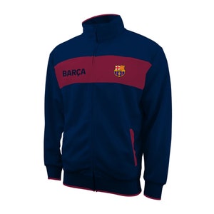 May include: A navy blue zippered jacket with a red stripe and the FC Barcelona logo. The text "BARÇA" is printed on the jacket.