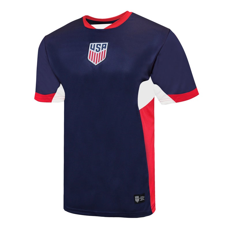 May include: Navy blue athletic jersey with red and white accents. The shirt features a USA crest on the chest and a red collar and sleeve cuffs. The side panels are red and white.