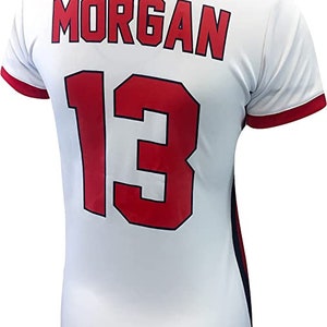 May include: White soccer jersey with red and blue trim. The back of the jersey has the name "MORGAN" and the number "13" in red with a black outline.
