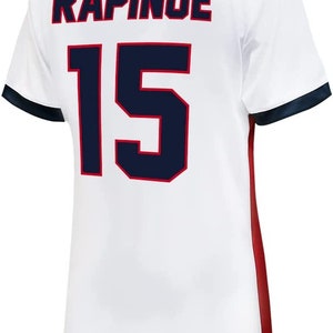 May include: White soccer jersey with blue and red trim. The back of the jersey has the name "RAPINOE" and the number "15" in blue.