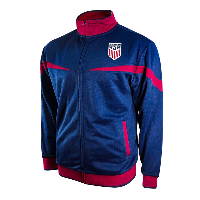 Puede incluir: Una chaqueta azul marino con cremallera, detalles rojos y un logotipo "USA" blanco en el pecho.
