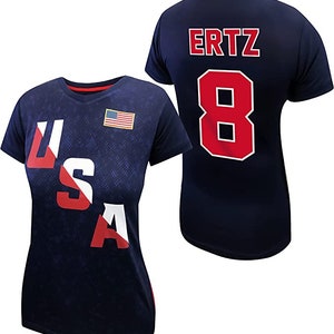 May include: Two navy blue t-shirts with red and white accents. One shirt has the word "USA" printed on the front in red, white, and blue. The other shirt has the name "ERTZ" and the number "8" printed on the back in red.