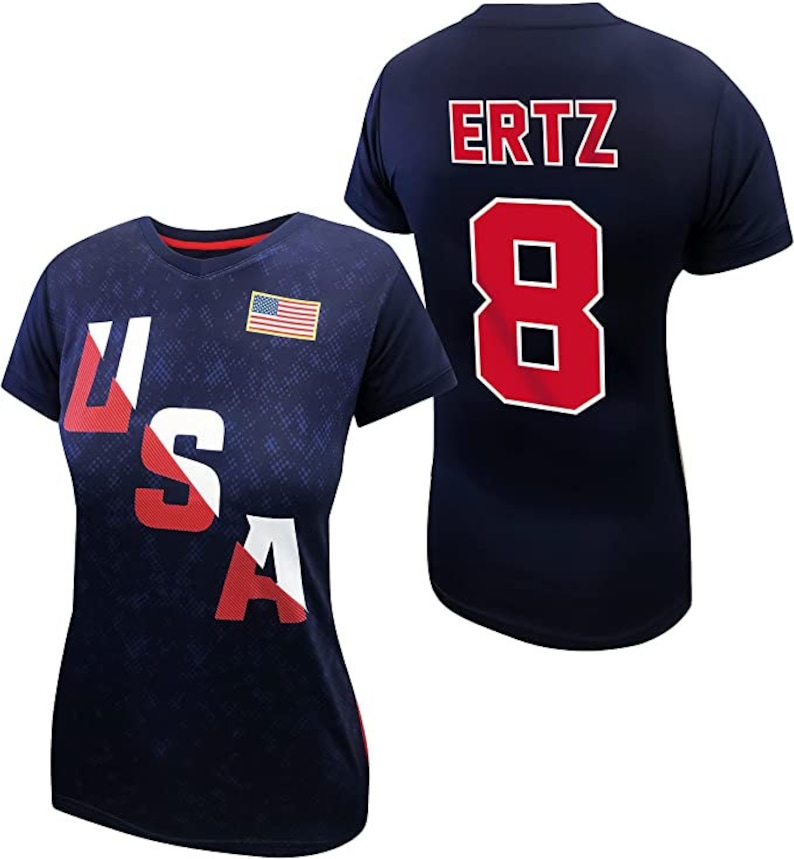 May include: Two navy blue t-shirts with red and white accents. One shirt has the word "USA" printed on the front in red, white, and blue. The other shirt has the name "ERTZ" and the number "8" printed on the back in red.