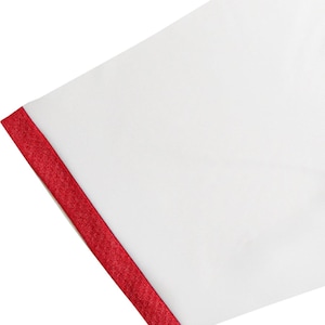 May include: Close-up of a white fabric with a vibrant red trim along the edge. The red trim has a textured appearance, creating a striking contrast against the smooth white surface. The fabric is angled.