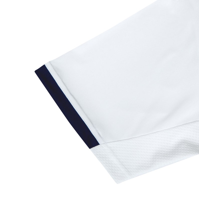 Pode incluir: Camiseta branca de manga curta com uma bainha azul marinho em torno da abertura da manga. A camiseta tem um painel de malha no lado.