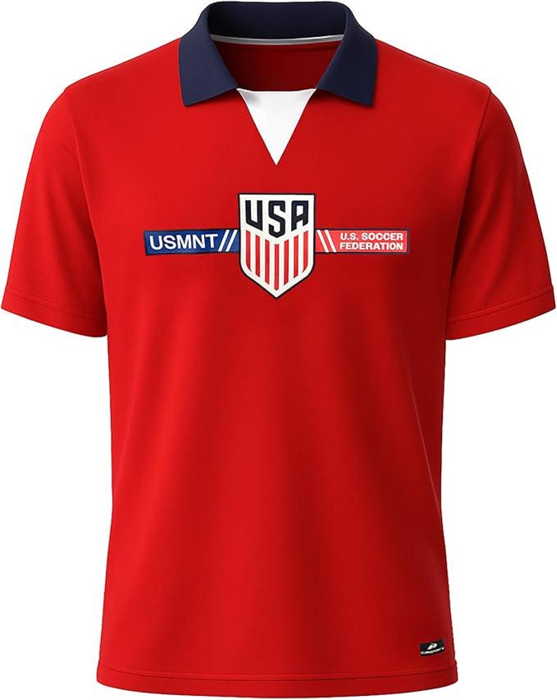 Puede incluir: Camiseta de f&uacute;tbol roja de manga corta con cuello azul marino y cuello en V blanco. La camiseta presenta el texto "USMNT" y "U.S. Soccer Federation" con un logotipo de escudo de EE. UU.