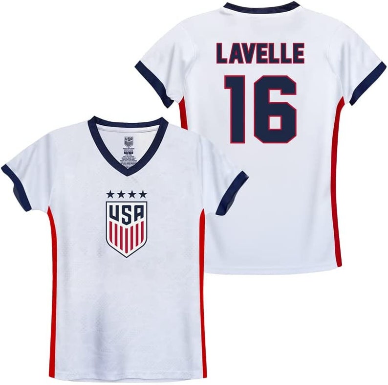 Op de afbeelding: Wit voetbaltenue met rode en blauwe bies. Het tenue heeft het USA-logo op de voorkant en de naam "Lavelle" en het nummer "16" op de achterkant.