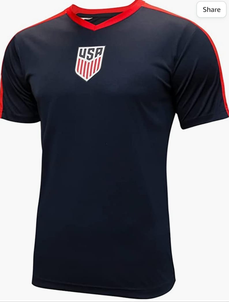 May include: A navy blue short-sleeved soccer jersey with red trim and the USA crest on the front.