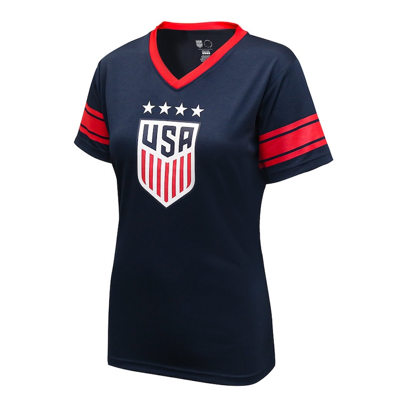 May include: A navy blue short-sleeved t-shirt with red and white stripes on the sleeves. The shirt features a white shield with red stripes and the word "USA" in white letters. Five white stars are above the shield.
