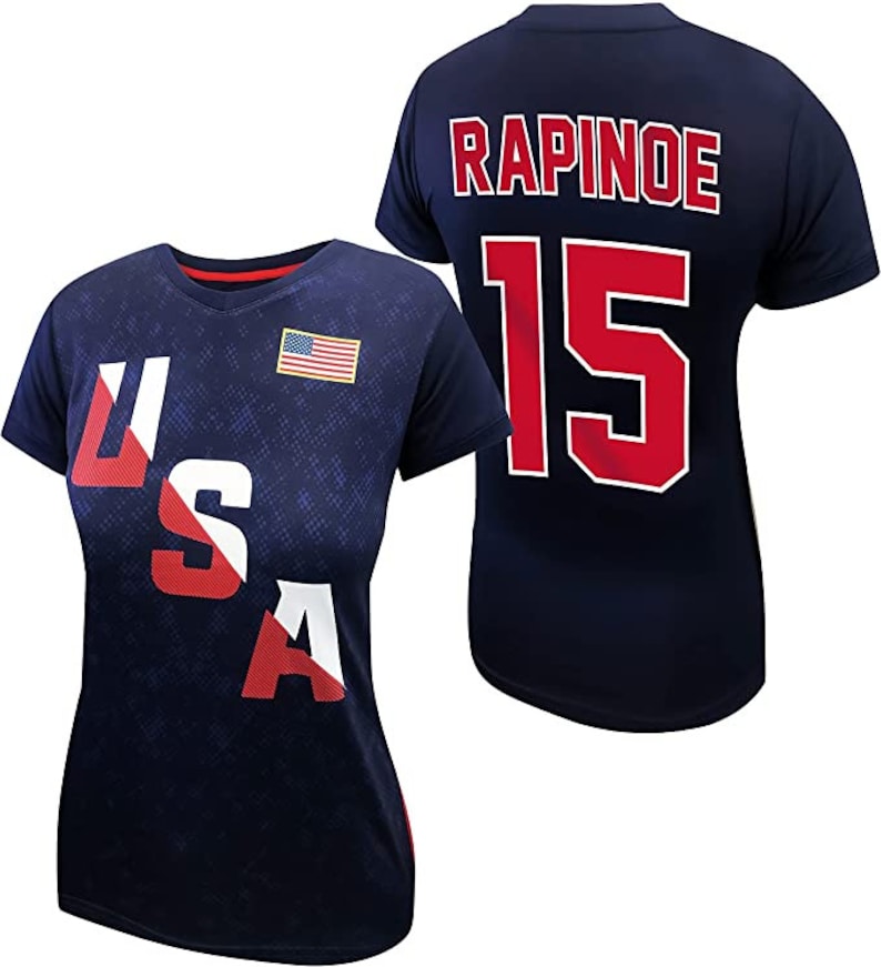 May include: A navy blue t-shirt with the text "USA" printed in red, white, and blue on the front and the text "RAPINOE 15" printed in red on the back.