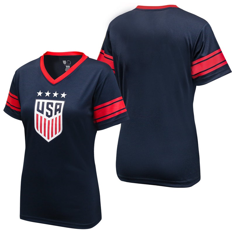 May include: Navy blue short-sleeved t-shirt with red and white stripes on the sleeves. The front of the shirt features a white shield with red and white stripes and the word "USA" in white letters. There are five white stars above the shield.