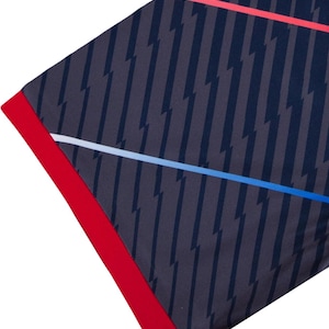 Peut inclure: Tissu bleu marine avec un motif d'&eacute;clairs gris fonc&eacute;. Le bord est bord&eacute; d'une bordure rouge vif. Des rayures blanches et bleues traversent le tissu en diagonale.