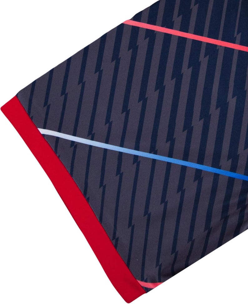 Peut inclure: Tissu bleu marine avec un motif d'&eacute;clairs gris fonc&eacute;. Le bord est bord&eacute; d'une bordure rouge vif. Des rayures blanches et bleues traversent le tissu en diagonale.