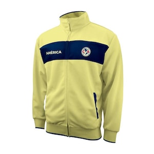 May include: A yellow zippered jacket with a navy blue stripe and the word "AMÉRICA" in white lettering. The jacket has a navy blue pocket on the right side and a team logo on the left side.