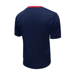May include: A navy blue short-sleeved t-shirt with a red trim around the neckline.