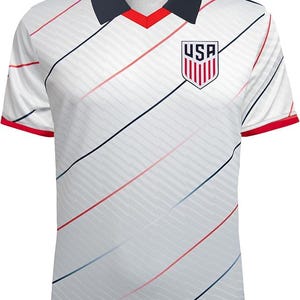 May include: White football shirt with red and blue diagonal stripes. The shirt features a navy blue collar and red sleeve trim. The USA emblem is on the chest.