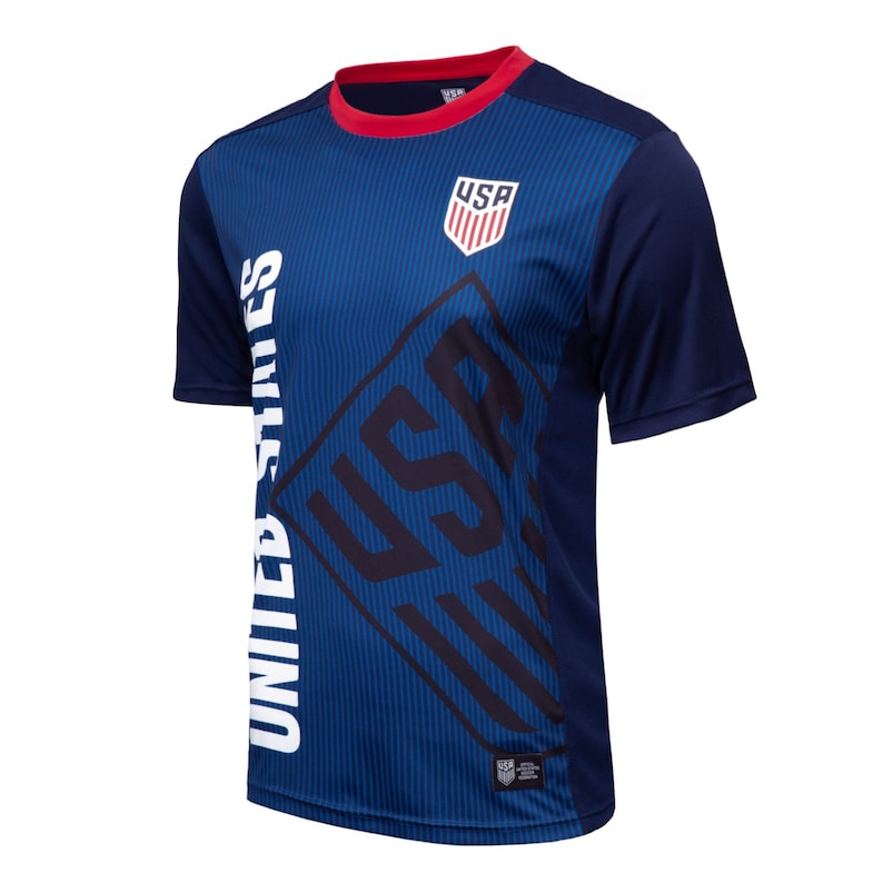 May include: A blue and white soccer jersey with the words "United States" and "USA" printed on it. The jersey has a red collar and a white crest with the letters "USA" inside.