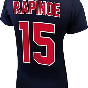 May include: A navy blue jersey with the name "RAPINOE" and the number "15" printed on the back in red with white outlines.