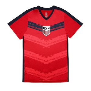 May include: Red soccer jersey with a navy blue V-neck collar and navy blue trim on the sleeves. The jersey has a white and blue USA logo on the front and a chevron pattern.