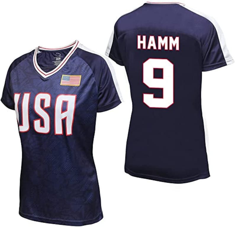May include: Navy blue athletic jersey with white accents. The front displays "USA" in white block letters, a small American flag, and a V-neck collar. The back features "HAMM" and the number "9" in white.