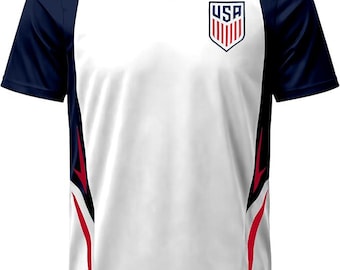 May include: A white V-neck short-sleeve jersey with navy blue sleeves and side panels. The front features a USA crest on the left chest, red and black graphic accents along the sides, and a small logo patch at the bottom left hem.