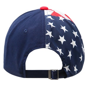 May include: A navy blue baseball cap with a white star pattern on the back half of the cap. The front of the cap is solid navy blue. The cap has a red button on top and a navy blue adjustable strap.