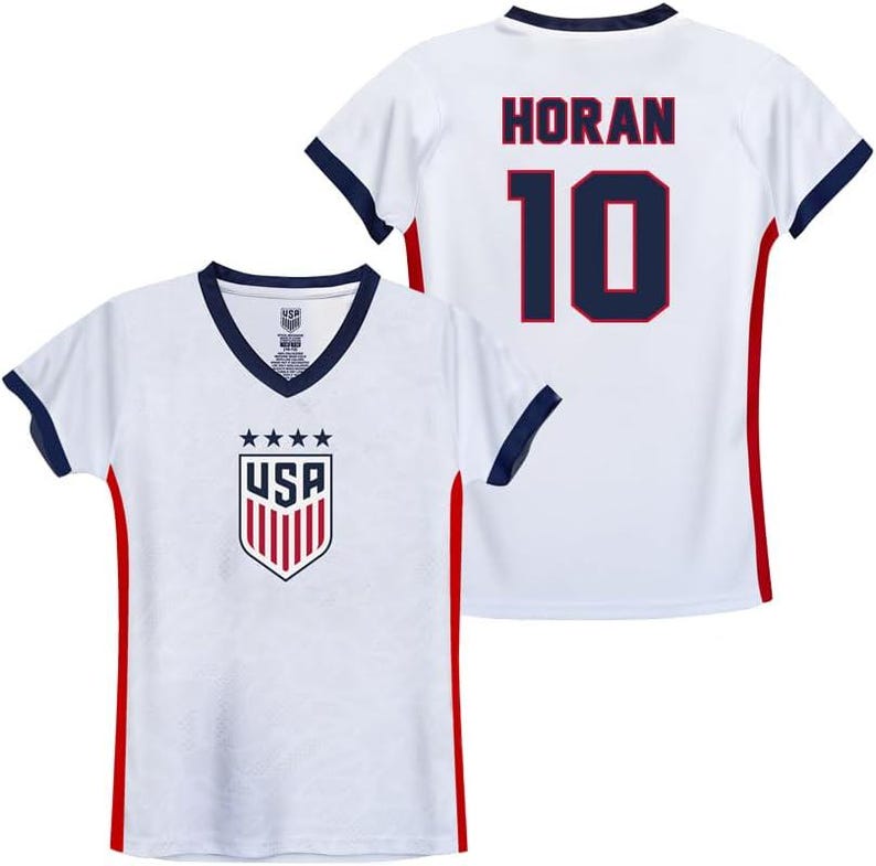 Pode incluir: Camisola de futebol branca com guarni&ccedil;&otilde;es vermelhas e azuis. A camisola tem o logotipo dos EUA na frente e o nome "HORAN" e o n&uacute;mero "10" nas costas.