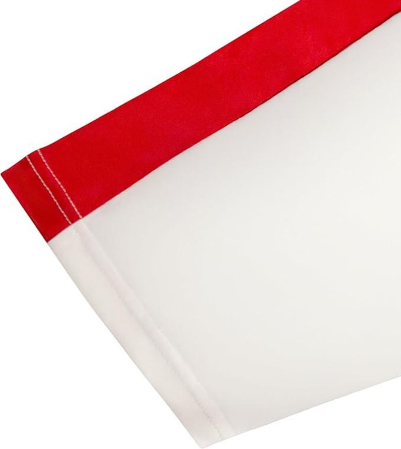 May include: Close-up of a white fabric with a red border. The red border is on the top edge of the fabric and is a solid color. The white fabric is a solid color. The fabric is folded at an angle.