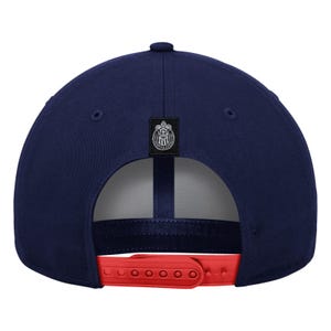May include: Navy blue baseball cap with a red adjustable strap. The cap features a team logo patch on the back and a button on top. The cap is a classic style, suitable for sports or casual wear.
