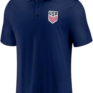 May include: A navy blue polo shirt with a white embroidered USA logo on the left chest.