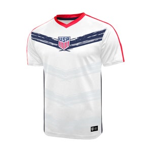 May include: White soccer jersey with red and blue trim. The jersey has a blue and white USA logo on the front with a brushstroke design.