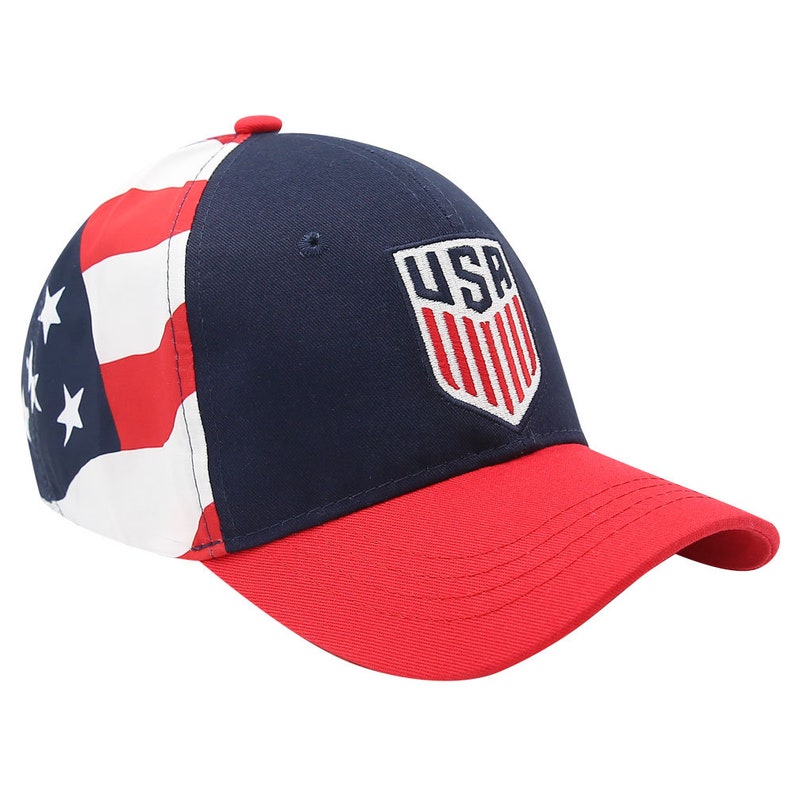 May include: A navy blue and red baseball cap with a white "USA" logo on the front. The side of the cap features a red, white and blue American flag design.