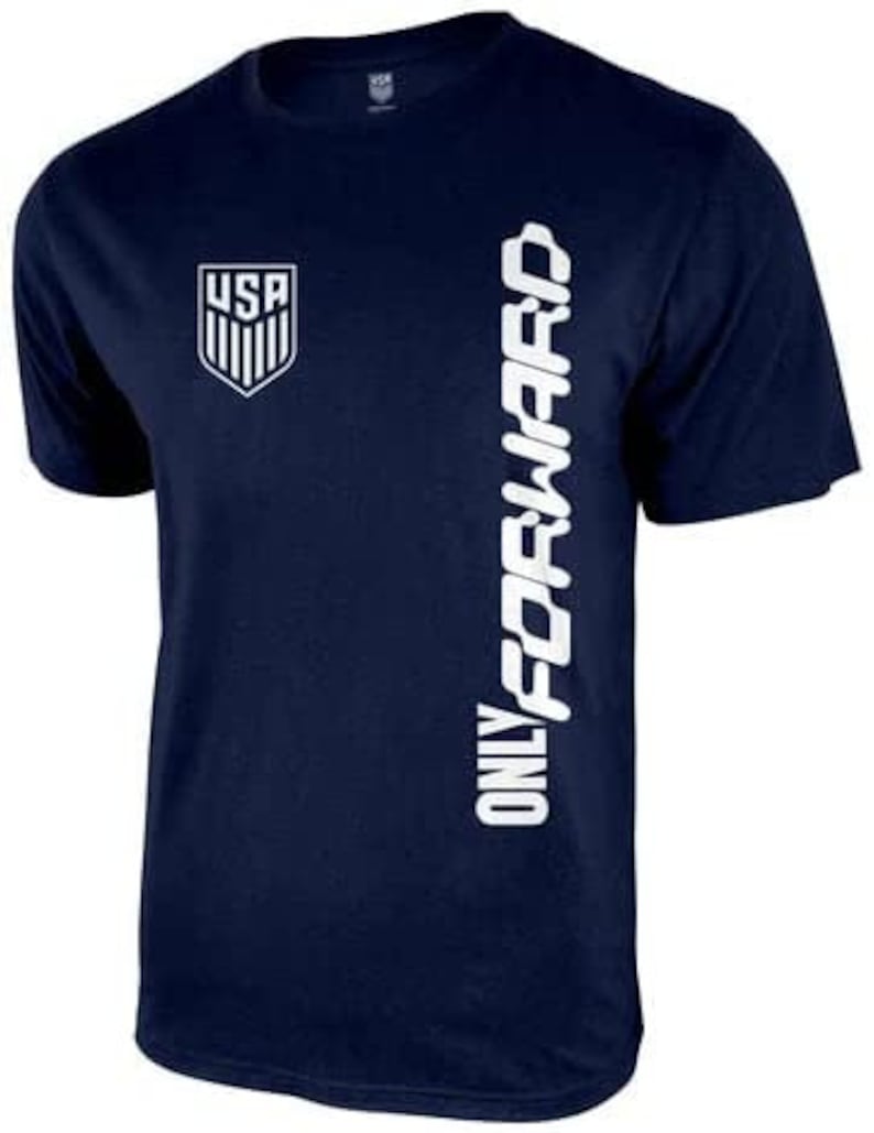 May include: A navy blue t-shirt with a white graphic of the USA soccer team logo and the text "ONLY FORWARD" on the right side.